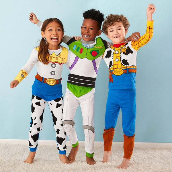 Three kids wearing Toy Story Buzz, Woody and Jessie pyjamas