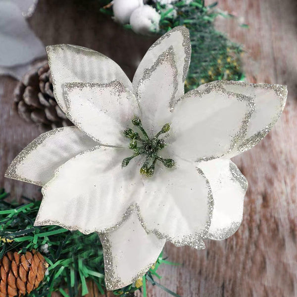 White glitter poinsettia flower against pinecones and timber