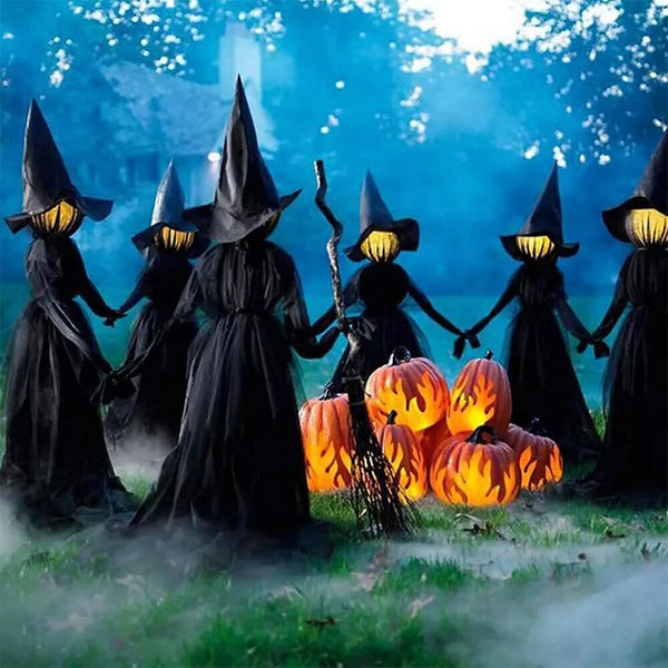 Light-up witch decorations posed around garden trees