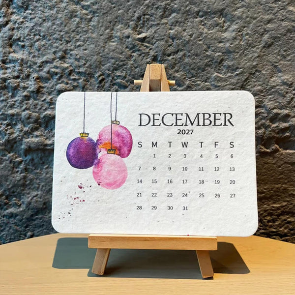 Seed paper mini desk calendar on a wooden table against a stone wall