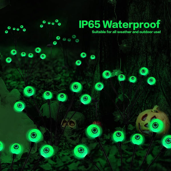 Solar eyeball lights pushed into a lawn for Halloween night