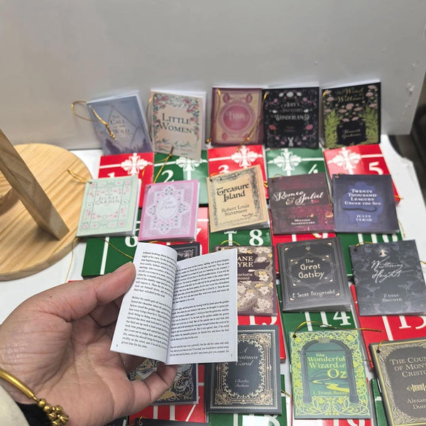 All 24 mini books laid out, with one opened to show its tiny pages