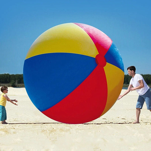 Family playing with a huge beach ball at the beach