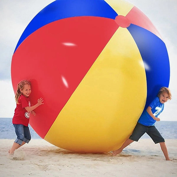 Kids pushing a giant beach ball on the sand