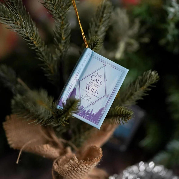 Mini book ornament with gold string hanging on a Christmas tree