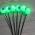 Solar Halloween eyeball lights glowing green in a garden bed at night