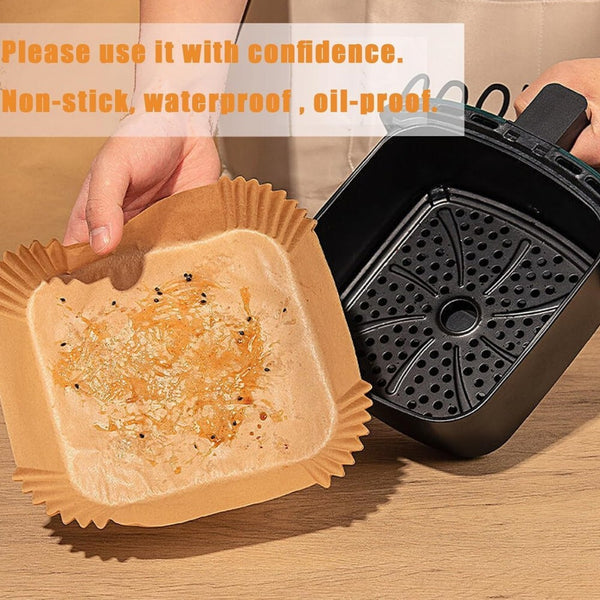 Hand placing a square paper liner into an air fryer basket