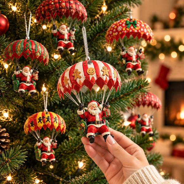 Hand holding a red and white Santa parachute ornament in front of a lit tree
