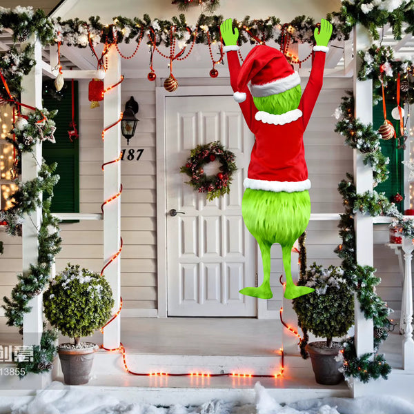 Christmas window decoration of green legs and a red Santa suit hanging on a front porch