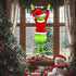 Green grump Christmas wall hanging with furry legs and Santa suit on a window beside a Christmas tree